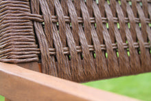Load image into Gallery viewer, Close-up of a woven wicker chair with a blurred green background