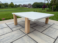 Load image into Gallery viewer, Square outdoor table with white top and wooden legs on a stone patio