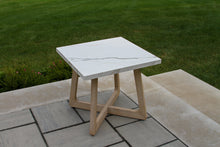 Load image into Gallery viewer, Small outdoor table with a stone top and wooden legs on a patio with grass in the background