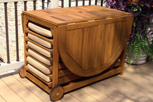 Load image into Gallery viewer, Wooden outdoor table with storage compartments on wheels, placed on a wooden deck.