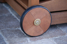 Load image into Gallery viewer, Wooden wheel with a metal hub on a stone pavement