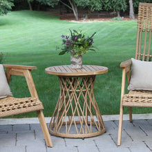Load image into Gallery viewer, Wicker chairs with a small round table on a patio, set against a grassy background.