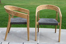 Load image into Gallery viewer, Two wooden chairs with woven seats on a grassy outdoor area.