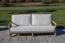 Load image into Gallery viewer, Outdoor wood sofa with light gray cushions on a patio area with grass and trees in the background