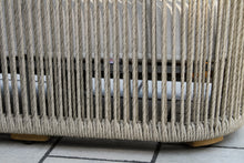 Load image into Gallery viewer, Close-up of a woven outdoor chair with wooden legs on a tiled floor.
