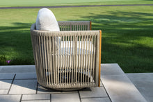 Load image into Gallery viewer, Wicker chair with cushion on a patio area with grass in the background