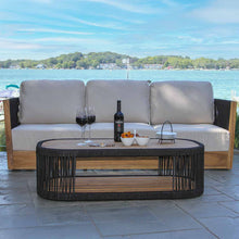 Load image into Gallery viewer, Outdoor patio set with a sofa and coffee table by a waterfront.
