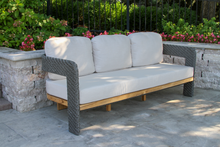 Load image into Gallery viewer, Outdoor sofa with light gray cushions on a stone patio with garden in the background
