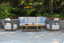Load image into Gallery viewer, Outdoor patio set with white cushions and a wooden coffee table on a stone patio.