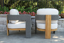 Load image into Gallery viewer, Two outdoor chairs with wicker frames and white cushions on a patio.