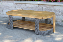 Load image into Gallery viewer, Wooden coffee table with wicker legs on a stone patio