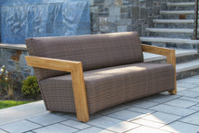 Load image into Gallery viewer, Brown wicker outdoor sofa with wooden armrests on a patio.
