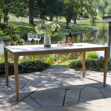Load image into Gallery viewer, Outdoor table setting with flowers, wine glasses, and a bottle by a pond
