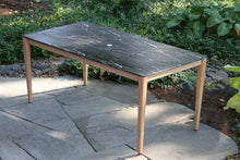 Load image into Gallery viewer, Outdoor table with a dark stone top on a stone patio
