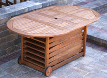 Load image into Gallery viewer, Wooden outdoor table with storage compartments on wheels in a patio setting.
