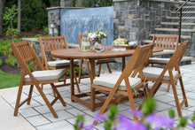 Load image into Gallery viewer, Wooden outdoor dining set with chairs and table on a patio with a water feature in the background.
