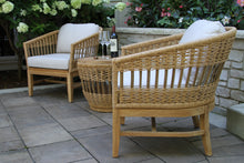 Load image into Gallery viewer, Wicker chairs with white cushions on a patio with a bottle of wine and glasses.
