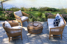 Load image into Gallery viewer, Outdoor patio set with wicker chairs and table on a stone patio by a body of water.

