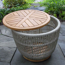 Load image into Gallery viewer, Round wooden table with a wicker base on a stone patio
