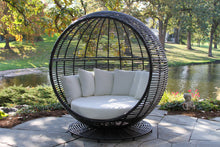 Load image into Gallery viewer, Spherical wicker chair with white cushions in a garden setting
