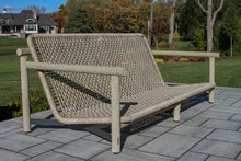 Load image into Gallery viewer, Woven outdoor lounge chair on a patio with a garden and house in the background
