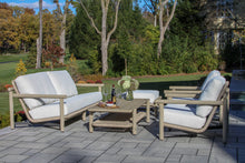 Load image into Gallery viewer, Outdoor patio furniture set with cushions on a stone patio, surrounded by trees and greenery.
