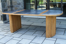 Load image into Gallery viewer, Outdoor dining table with wooden legs and a dark top on a tiled patio.
