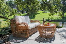 Load image into Gallery viewer, Outdoor patio set with wicker furniture and a table by a pond
