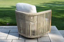 Load image into Gallery viewer, Wicker chair with a white cushion on a patio with grass in the background
