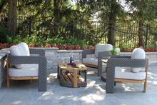 Load image into Gallery viewer, Outdoor patio set with wicker chairs and a coffee table on a stone patio.
