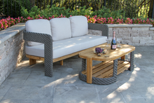 Load image into Gallery viewer, Outdoor patio set with a sofa and coffee table on a stone patio.
