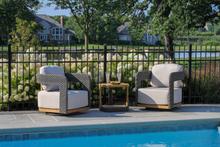 Load image into Gallery viewer, Two wicker chairs with white cushions by a poolside
