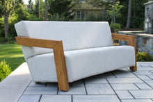 Load image into Gallery viewer, White outdoor sofa with wooden armrests on a patio
