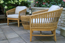 Load image into Gallery viewer, Wicker chairs with white cushions on a patio with a bottle of wine and glasses.
