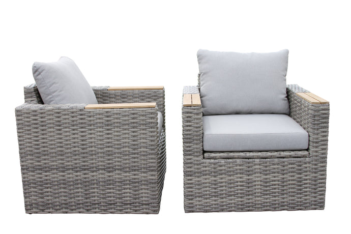 A teak and wicker captain's chair with a grey cushion, paired with a matching wicker ottoman and accent table.
